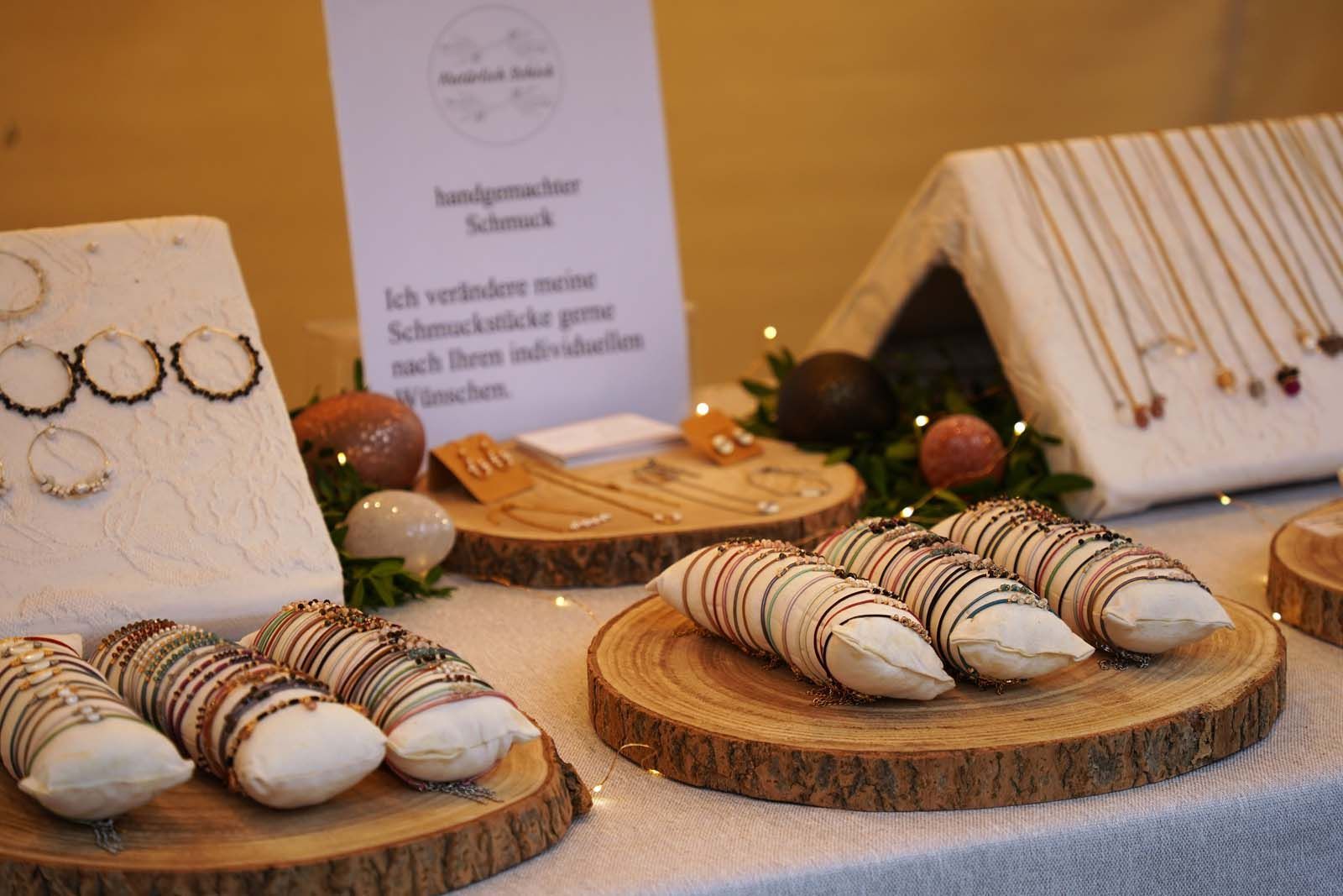 Marleen Mroseck mit 'Natürlich Schick' Auslage von Natürlich schick: Edelsteinschmuck und Perlen auf Baumscheiben und weißen Stoffbrettern – liebevoll arrangiert