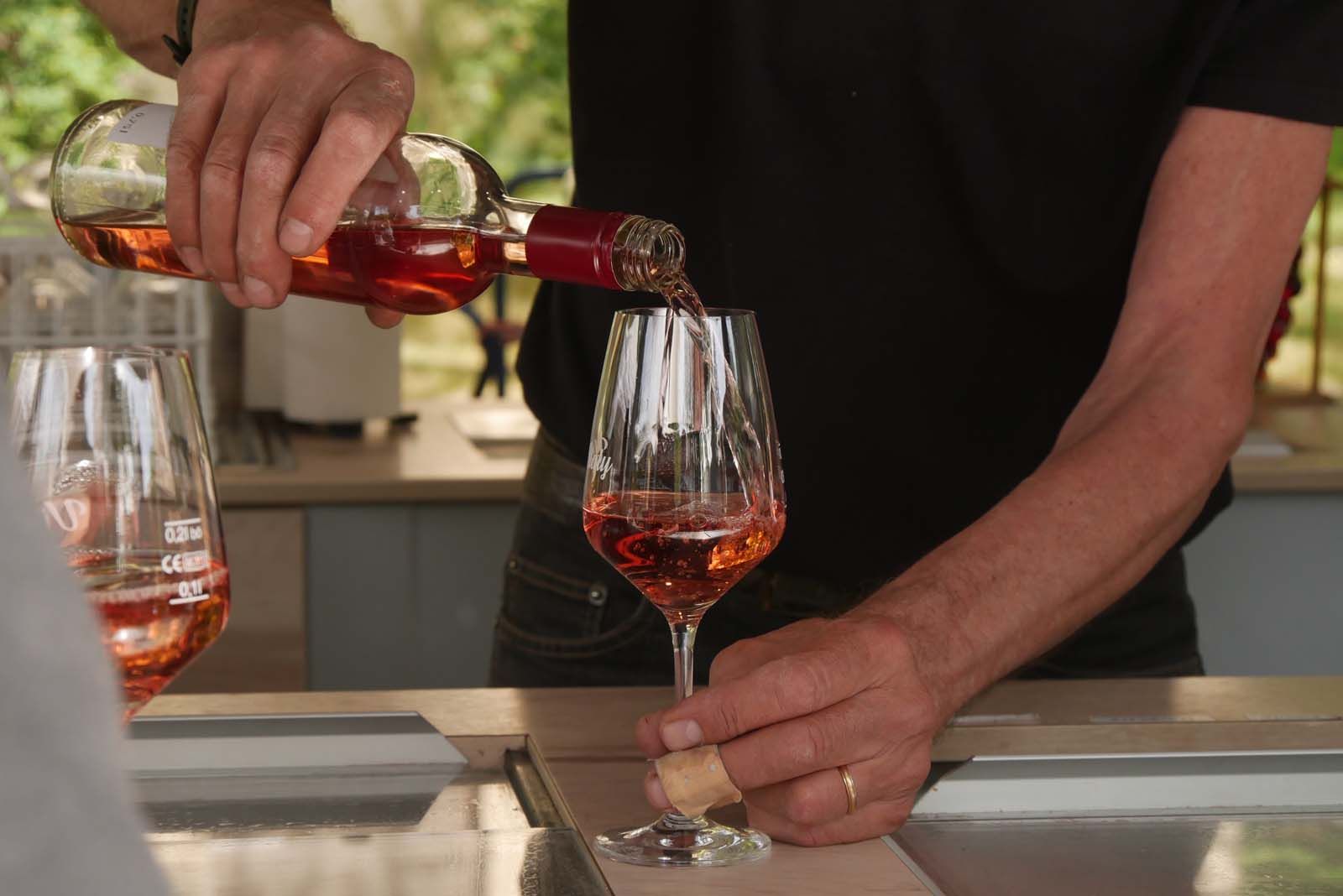 Mauro Francia schenkt an seinem Weinstand ein Glas Rotwein ein.