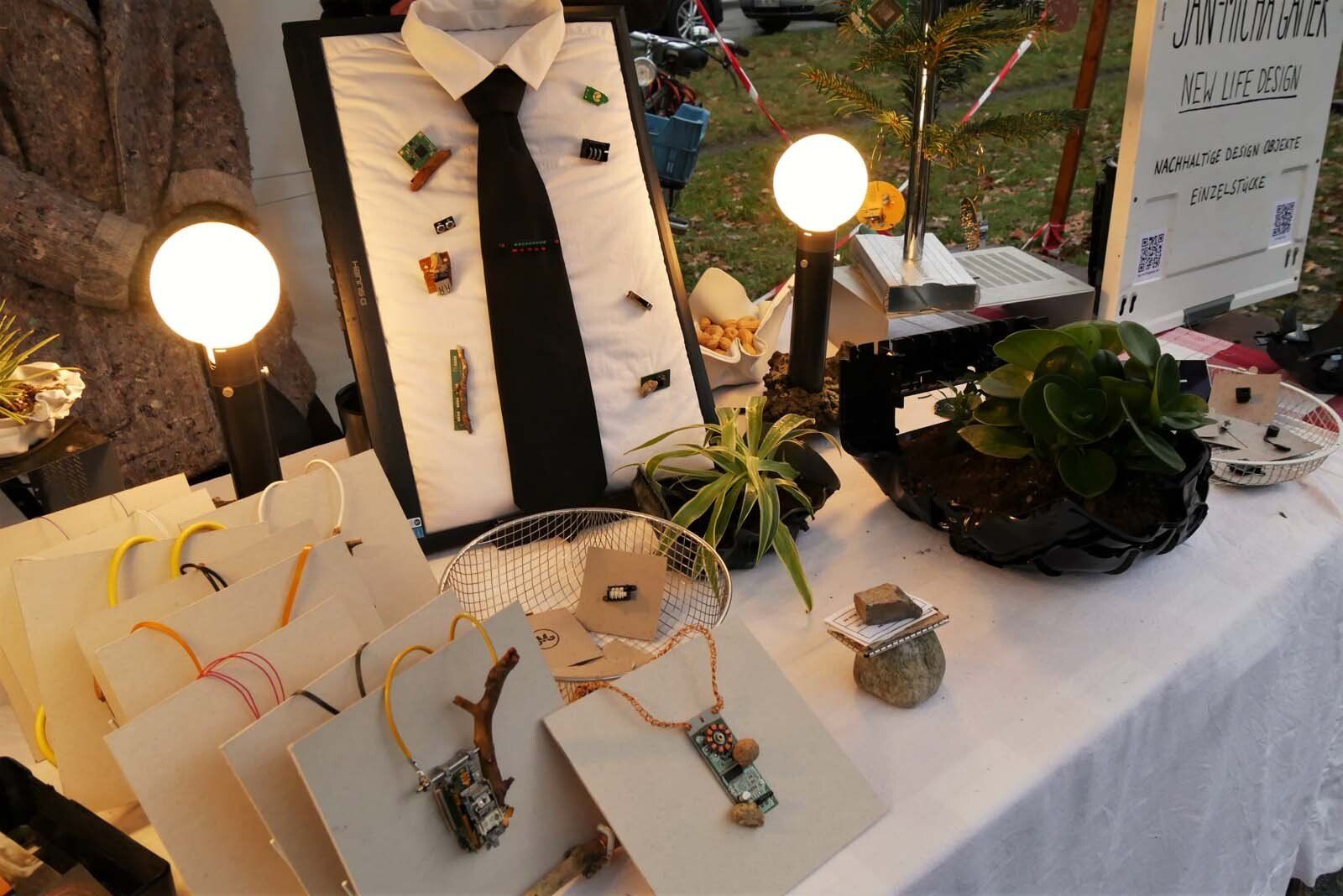 Jan-Micha Gamer startet sein findungsreiches Dasein bei Weihnachten in Westend sowie dem kunsthandwerklichen ADVENT am Karl-August-Platz mit Aus Elektroschrott und anderen Materialien hergestellte Pflanzschalen, Ketten, Broschen und Ohrstecker sowie Leuchten und Wohnaccessoires (Schalen, kleine Wandregale und Collagen).