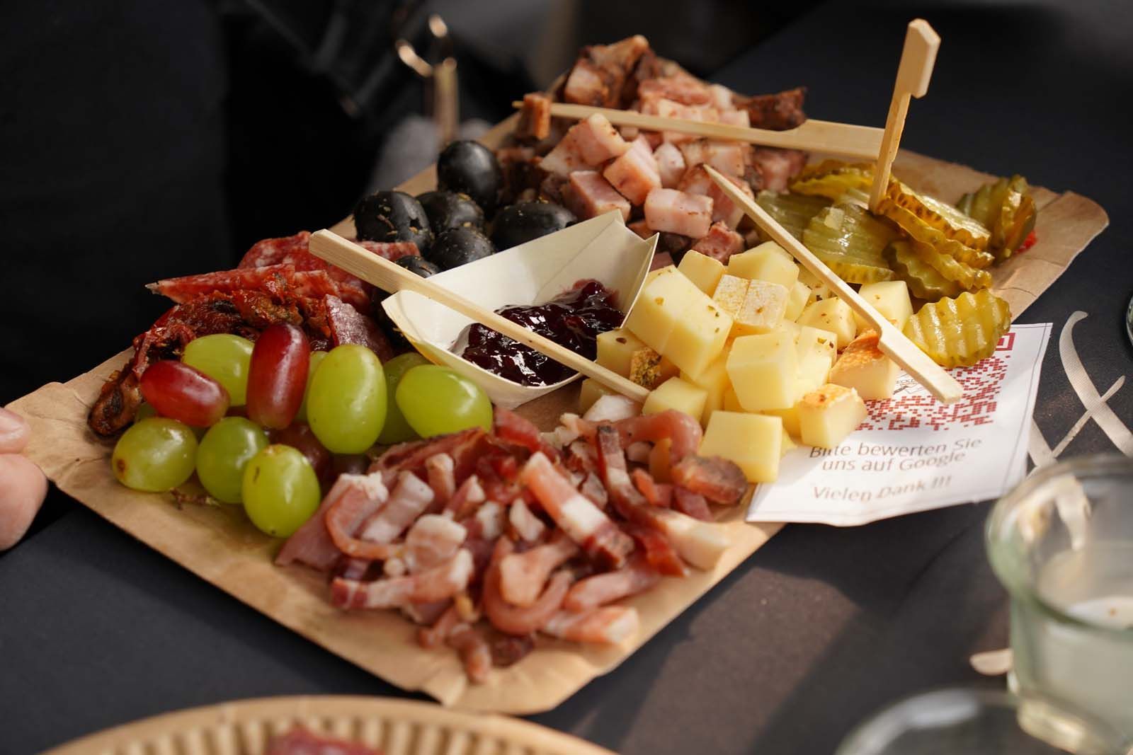 Ein Teller mit Speck, Käse, Oliven, Gewürzgurke und Trauben lädt beim WeinPfingsten 2025 zum Teilen und Genießen ein