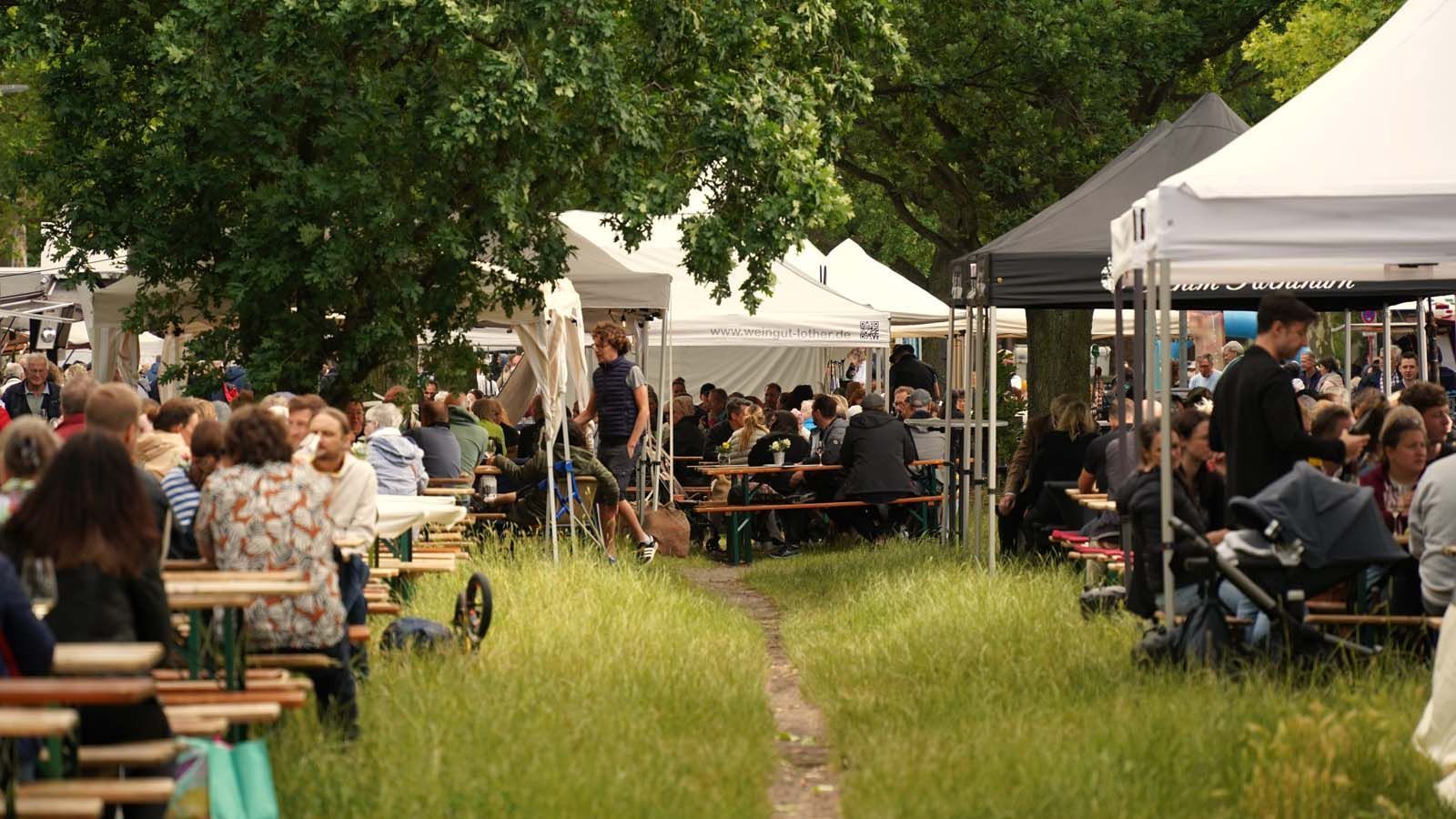 WeinPfingsten in Westend gut besucht! Man sitzt zur Rechten und zur Linken an Tischen unter Bäumen oder unter Zelten - es könnte ja regnen!