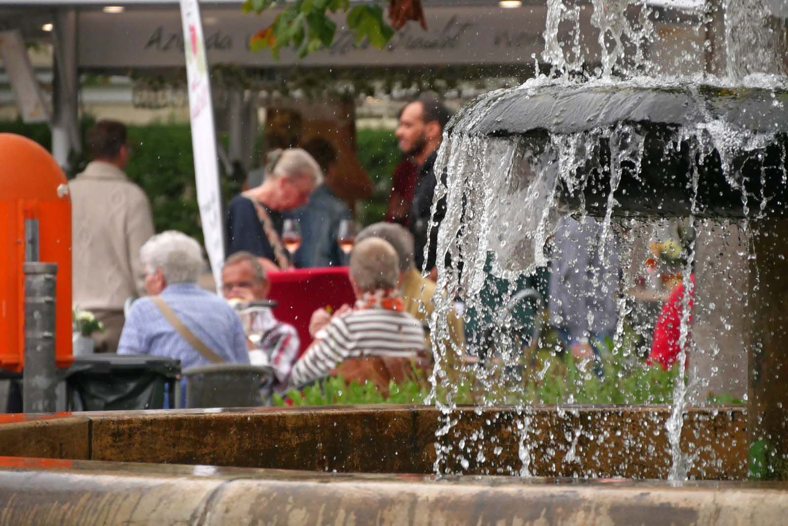 Der Wappenbrunnen in Berlin-Steglitz-Zehlendorf mit seinen Gästen am Ludwig-Beck-Platz Wappenbrunnen und Gäste beim ersten Weinfrühling am Ludwig-Beck-Platz in Steglitz-Zehlendorf