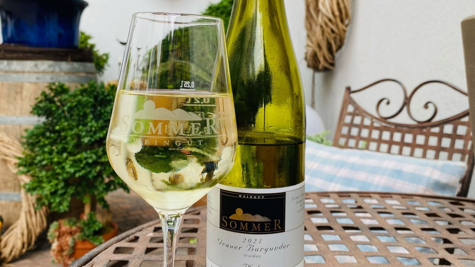 Auf einen schönen Weinfrühling am Ludwig-Beck-Platz! Grauer Burgunder im Glas mit Flasche im Hintergrund – Weißweingenuss vom Weingut Sommer