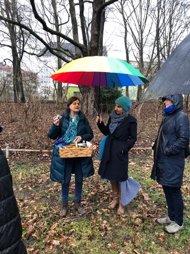 Wildkräuterführung anlässlich des kunsthandwerklichen OSTERMARKTS am Karl-August-Platz. Zu sehen ist Sigrid Künstner bei der Wildkräuterführung im Volkspark Schöneberg (Rudolph-Wilde-Park), der gleich neben dem Rathaus Schöneberg beheimatet ist. Es großer bunter Regenschirm ist aufgespannt. Denn am 10. März 2023, als die Führung anlässlich des Netzwerktages des Unternehmerinnen-Netzwerks Tempelhof-Schöneberg stattgefunden hat, ging es regnerisch zu.