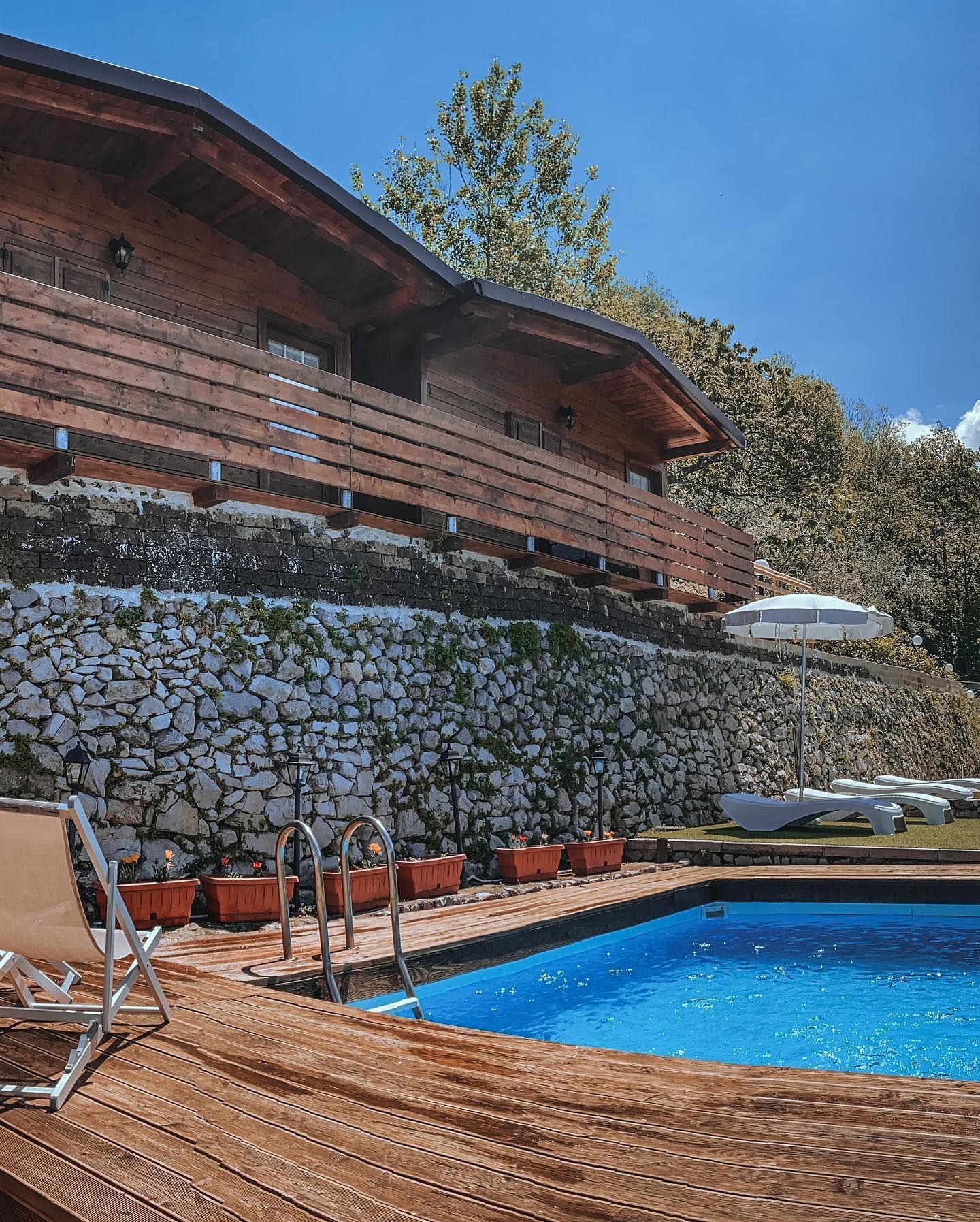 Area esterna della struttura con piscina, ombrelloni e sdraio.