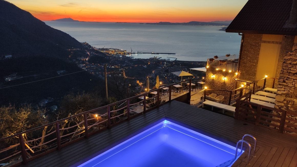 Piscina illuminata della struttura e tramonto sullo sfondo.