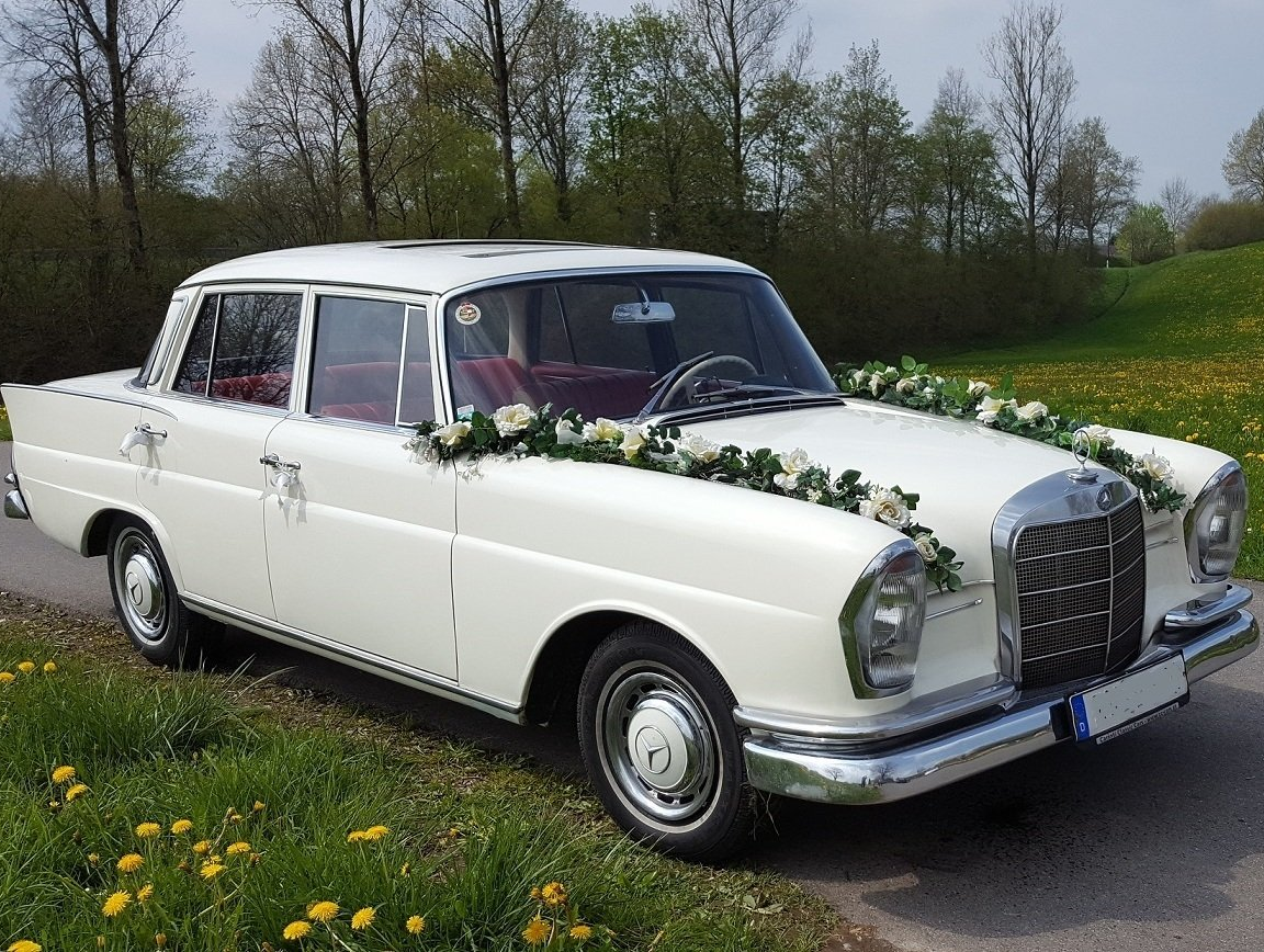 Die Oldtimer Limousine mit parallel laufenden Girlanden auf der Motorhaube. Autoschmuck Hochzeit Bilder