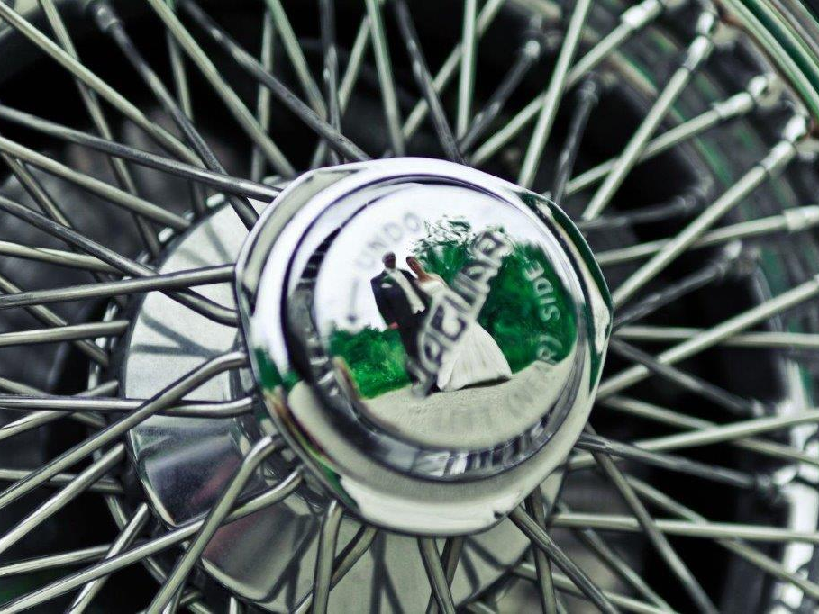Schönes Motiv des Hochzeitsfotografen - Brautpaar spiegelt sich im Oldtimer Speichenrad Hochzeit Oldtimer
