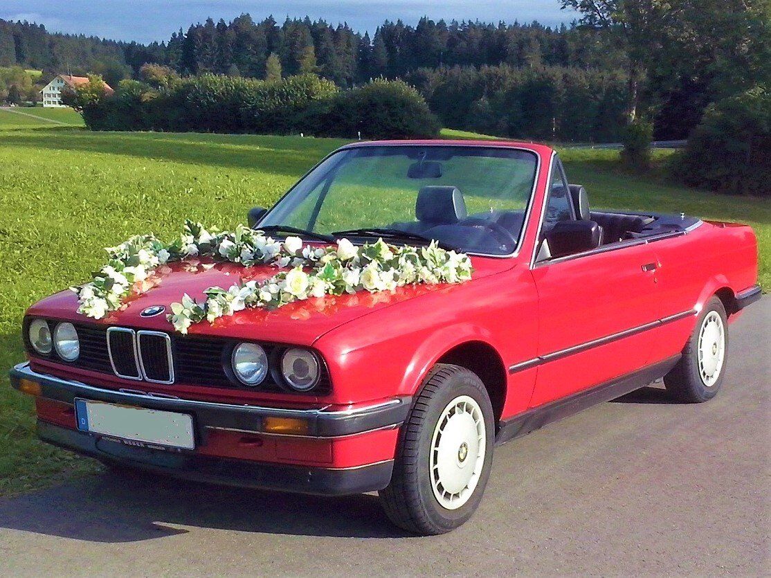 Schön geschmückt, bei herrlichem Hochzeitswetter, fährt der BMW das Brautpaar zur Kirche. Hochzeitsauto mieten Allgäu
