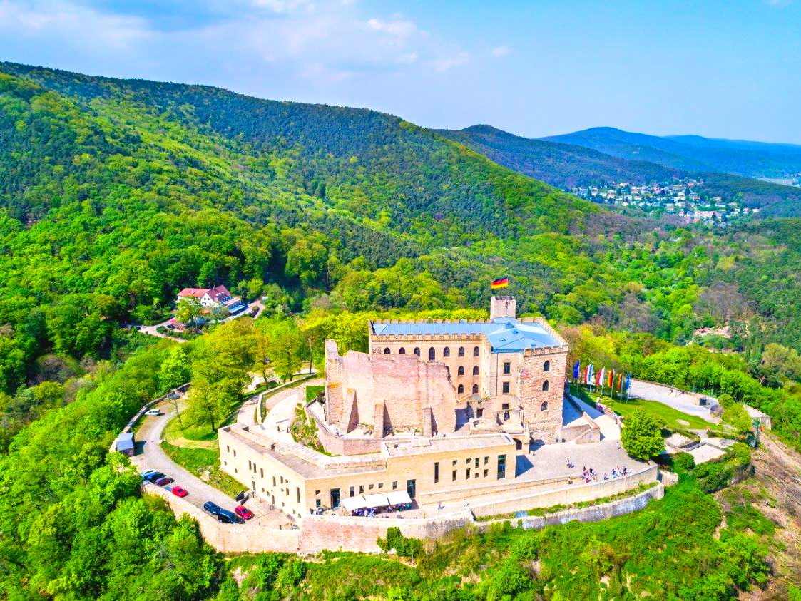 Oldtimerbus mieten: Weinstraße, Hambacher Schloss und Neustadt an der Weinstraße. Heute feiern Brautpaare im Hambacher Schloss ihre Hochzeit. 1832 wehte auf dem Hambacher Schloss zum ersten Mal die schwarz-rot-goldene Fahne. Beim Hambacher Fest wurde auch zum ersten Mal die Einheit Deutschlands gefordert, die Pressefreiheit und die Gleichberechtigung der Frauen. Das Hambacher Schloss über Neustadt gilt als die Wiege der Deutschen Demokratie. Oldtimerbus mieten Weinstraße Neustadt-an-der-Weinstraße
