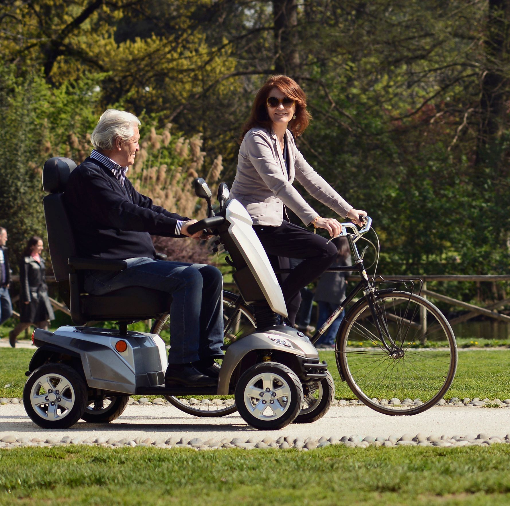 Eine Person auf einem Elektromobil und eine Frau auf einem Fahrrad