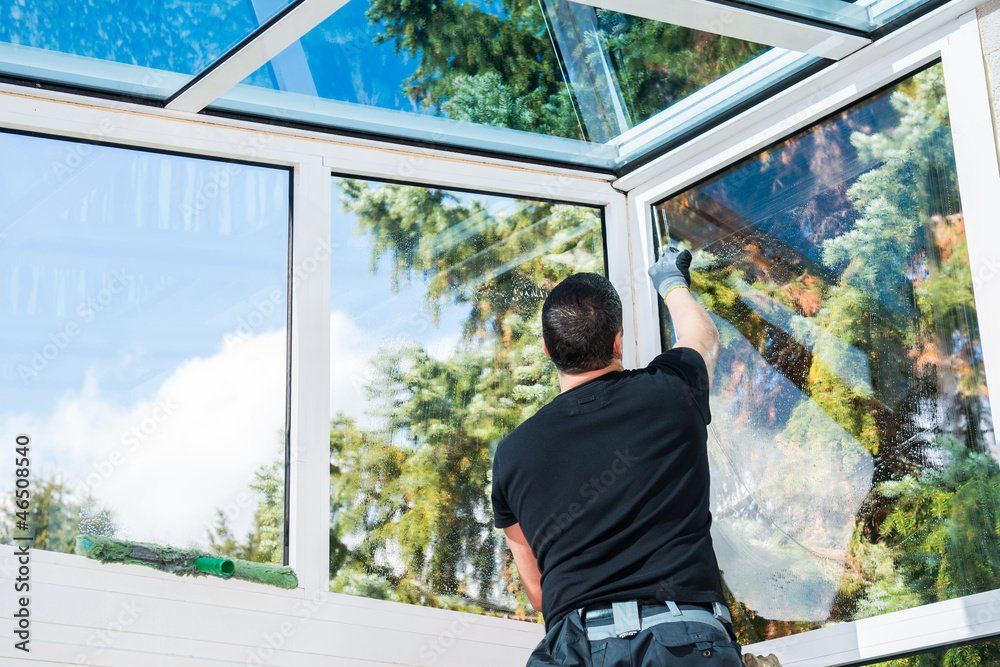 Homme qui nettoie les vitres d'une véranda