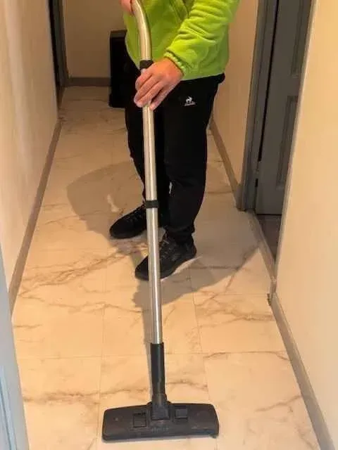 Un homme utilisant un aspirateur dans un couloir.