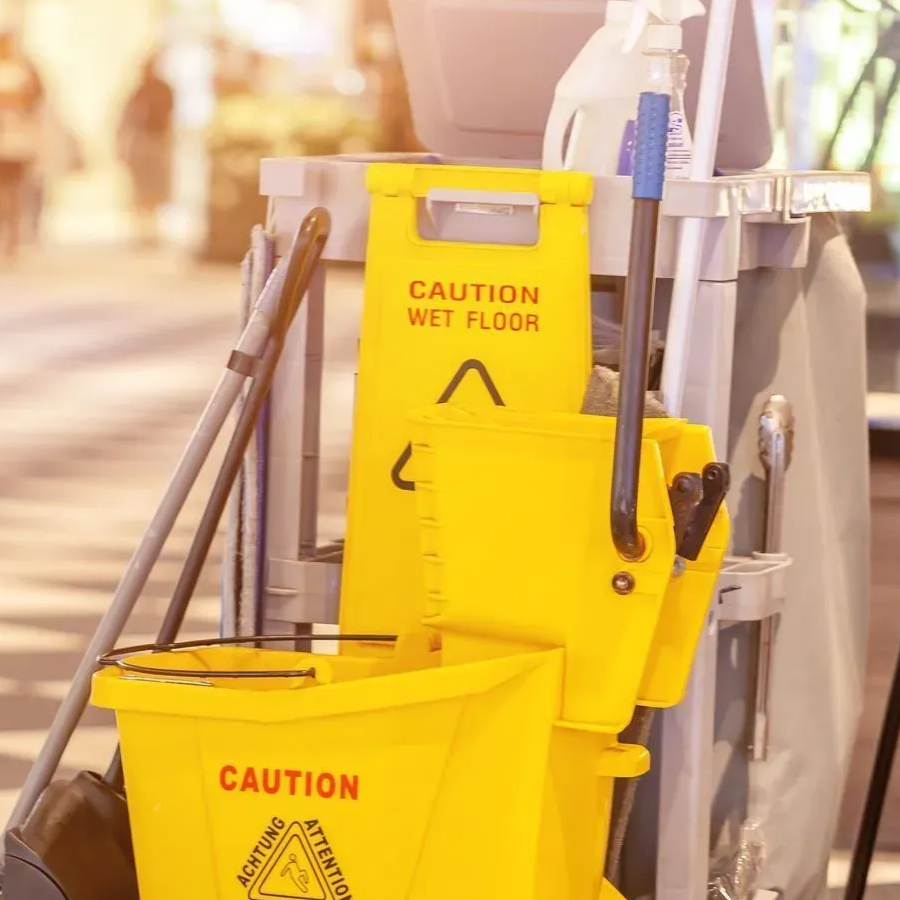 Chariot de nettoyage avec seaux jaunes et balai dans un espace public