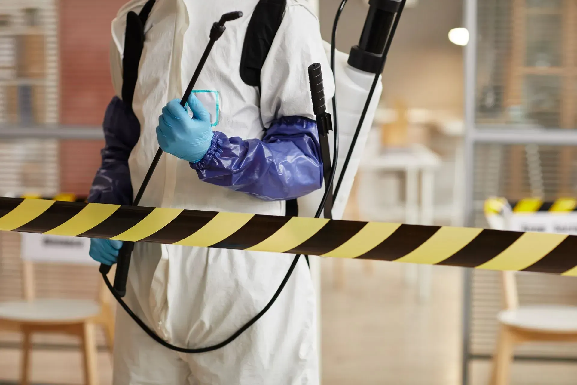 Homme en combinaison blanche qui désinfecte des lieux
