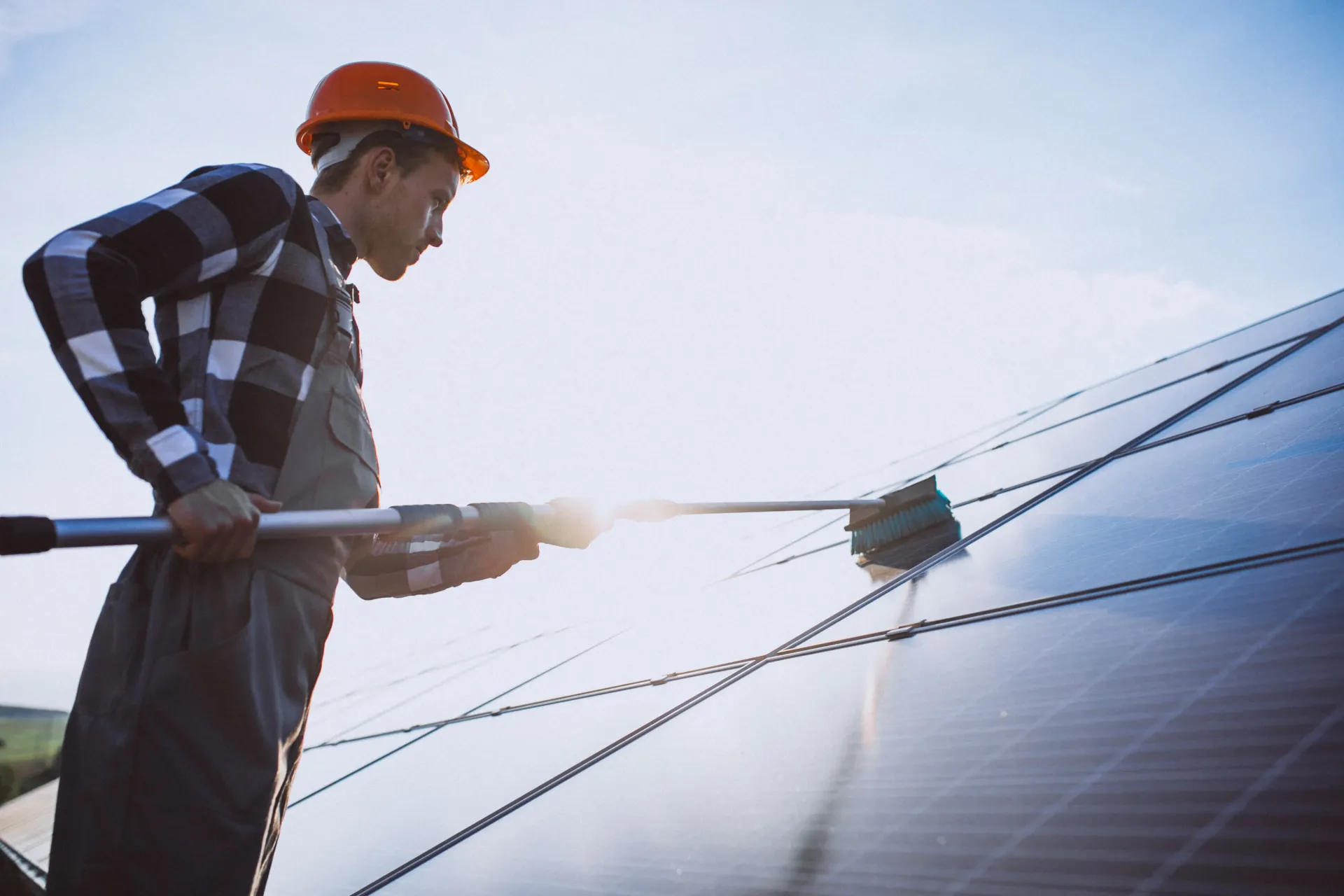 Un homme en tenue de travail nettoie des panneaux solaires