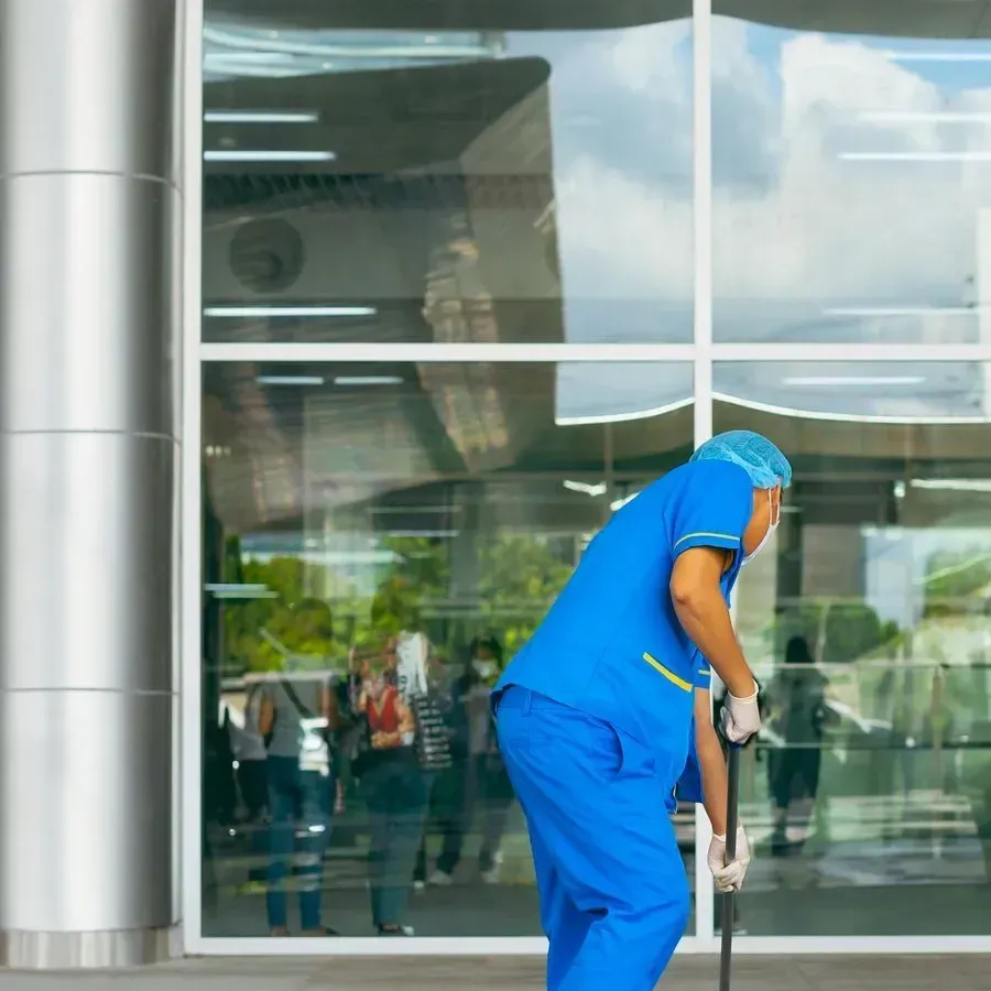 Personnel d'entretien en uniforme bleu nettoyant le sol