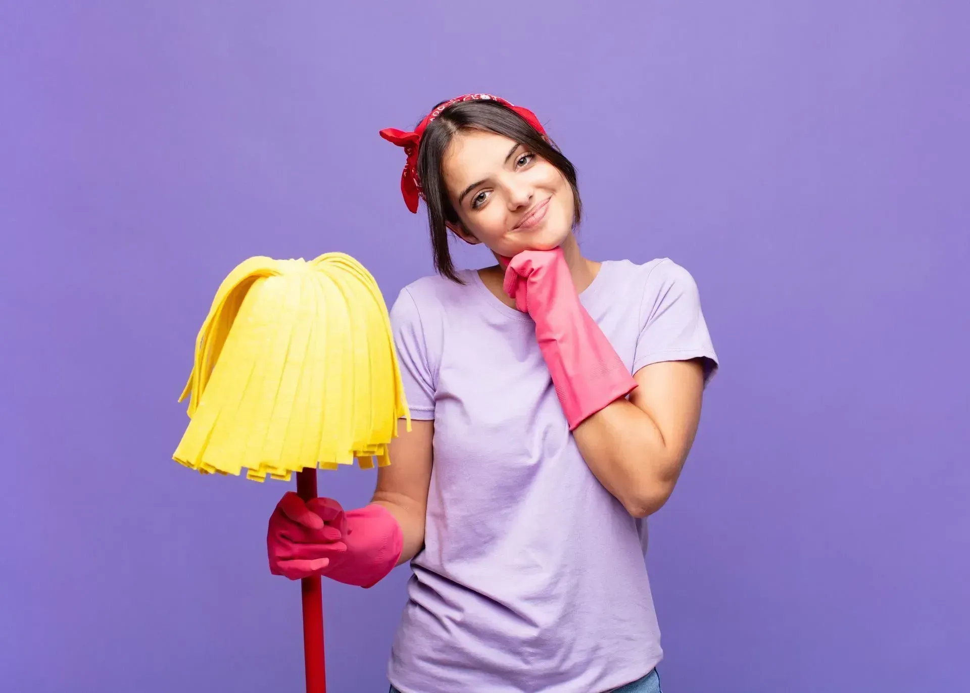 Femme souriante tenant un seau jaune et portant des gants roses