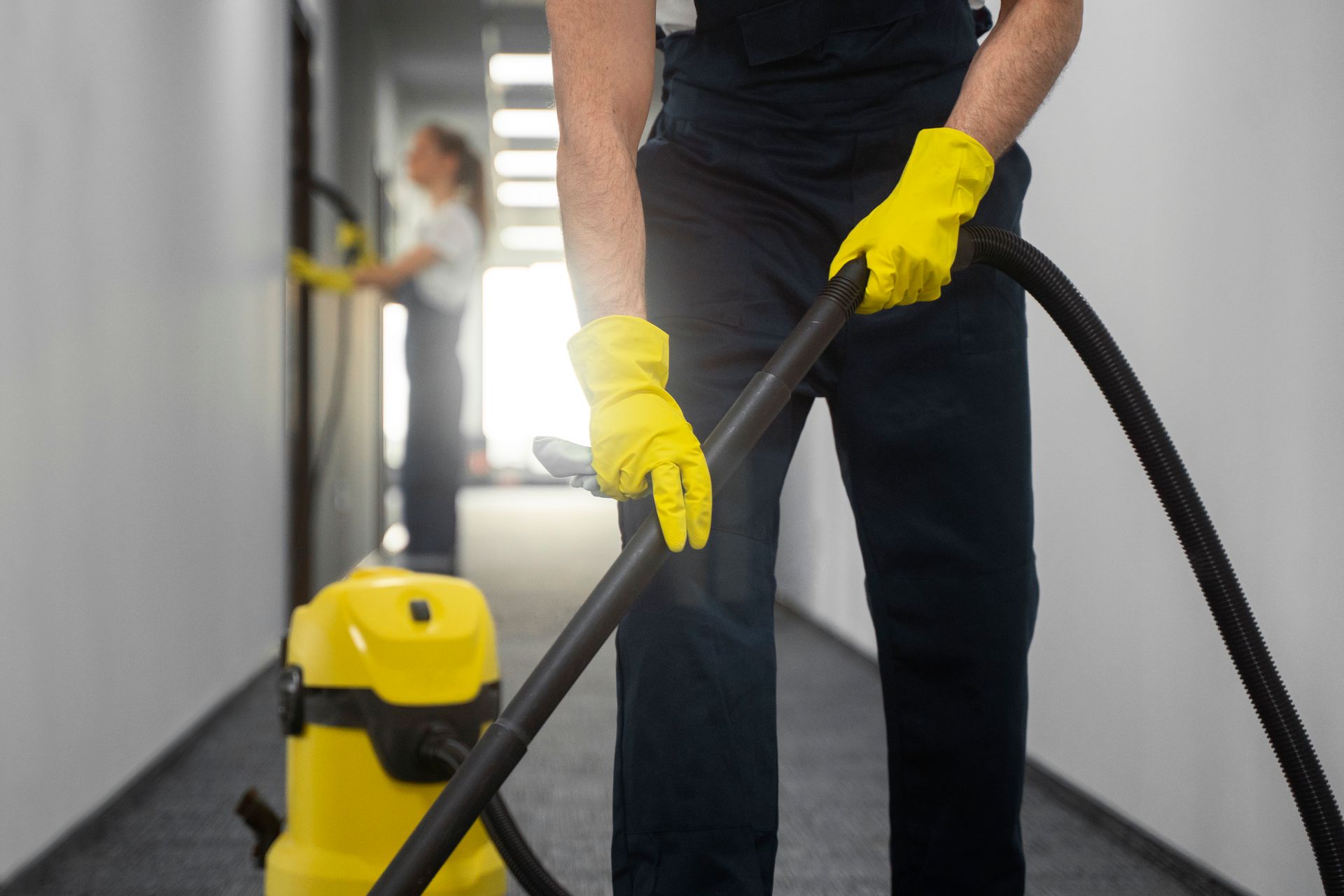 Un homme qui passe l'aspirateur dans un couloir pour nettoyer les sols