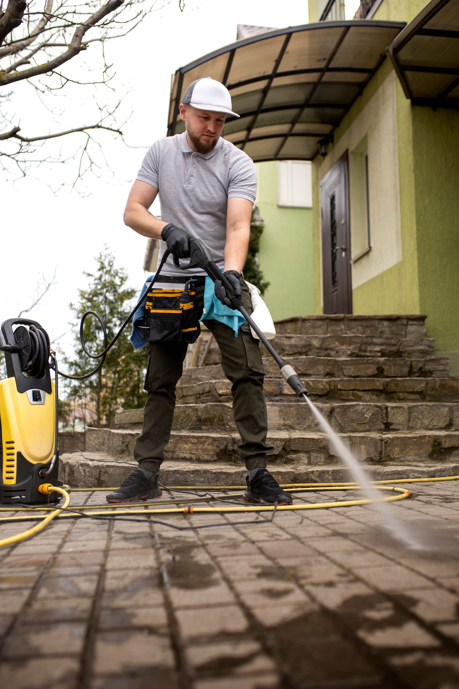 Homme qui nettoie à l'aide d'un karcher une terrasse avec des escaliers