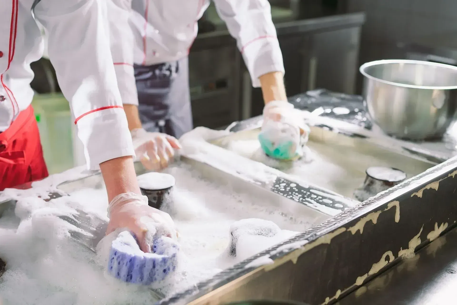 Équipe de cuisine en train de laver des ustensiles dans une cuisine professionnelle