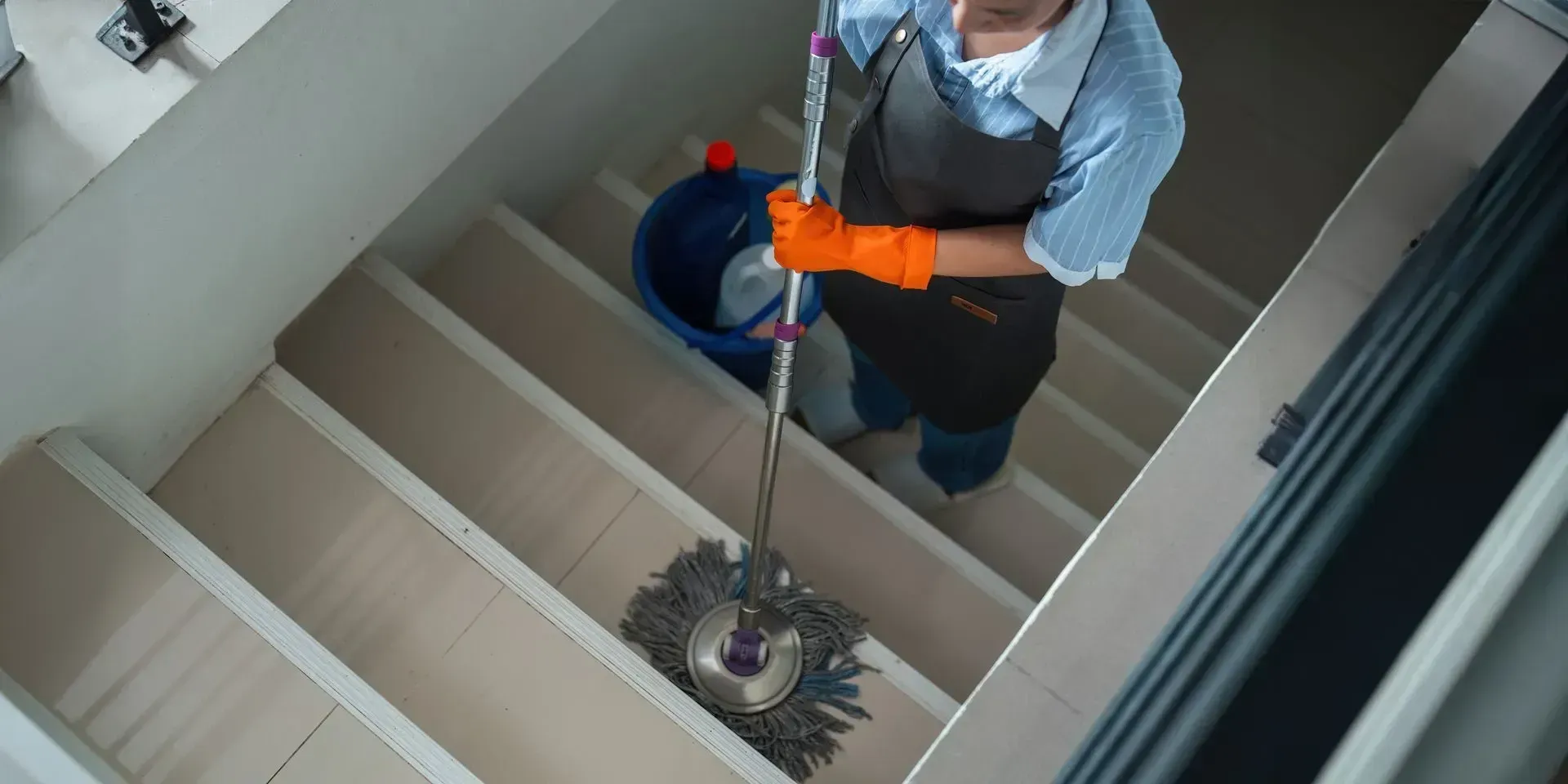 Femme en train de nettoyer les escaliers avec un balai