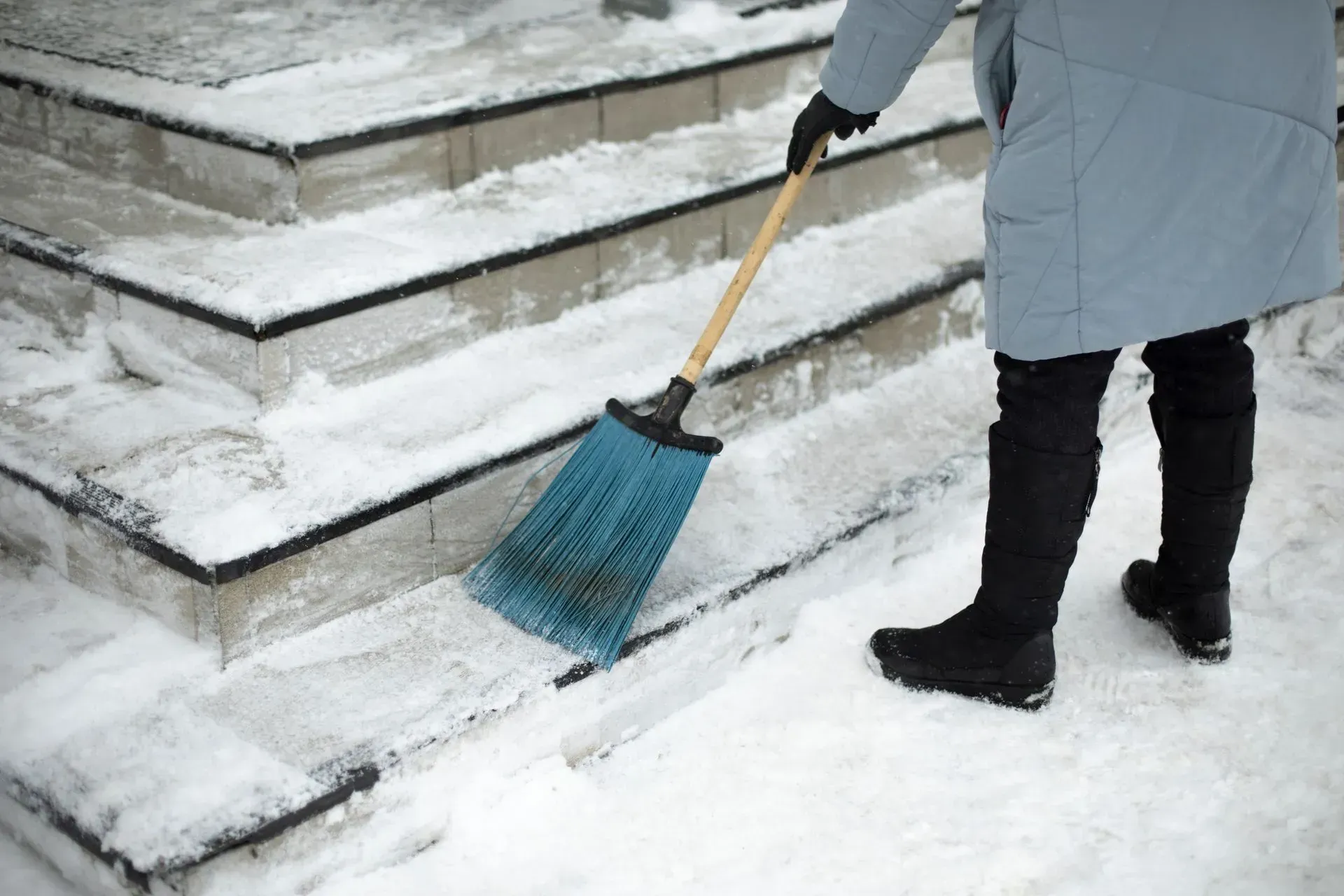 Une personne balaie des escaliers recouverts de neige