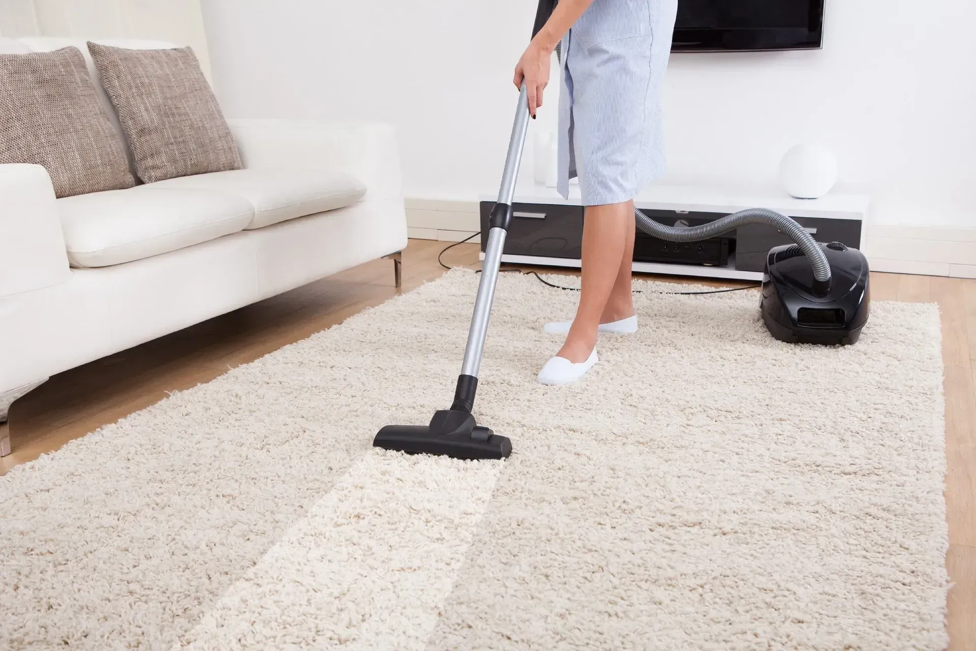 Femme nettoyant le tapis avec un aspirateur dans un salon moderne