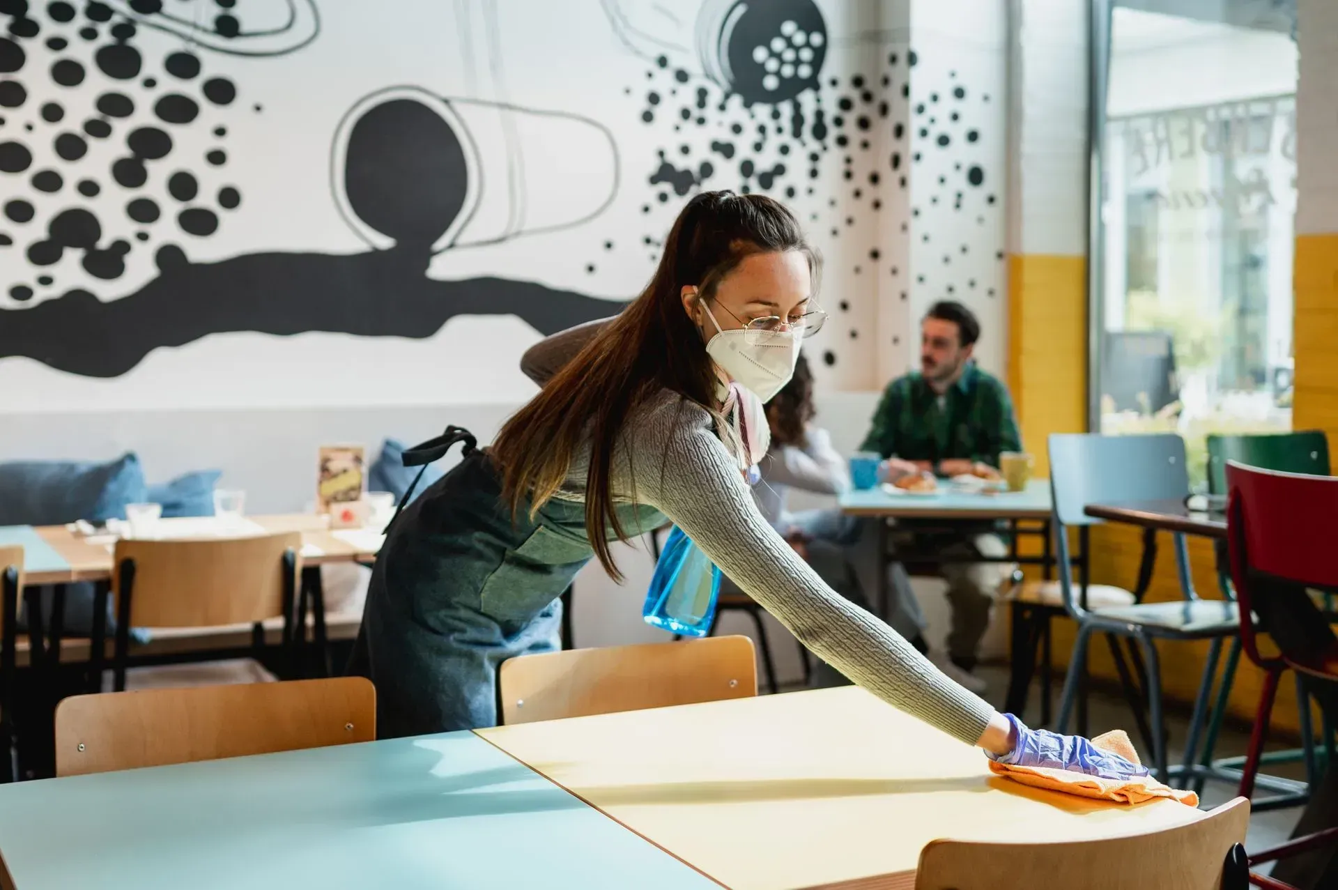 Une employée nettoie une table dans une classe