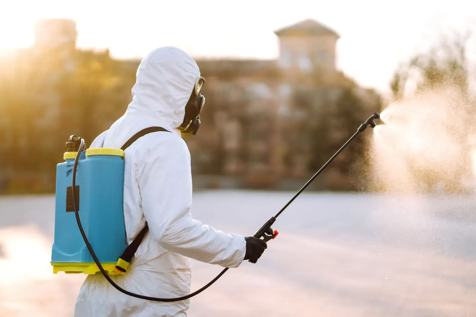 Un homme en combinaison de protection pulvérise un produit chimique