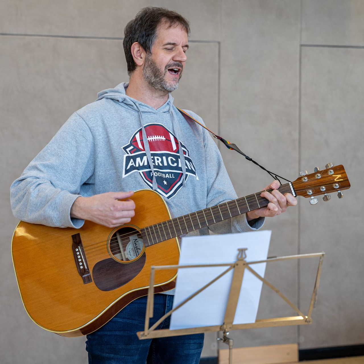 Lehrkraft Herr Remspecher spielt Gitarre zu St. Martin in der Turnhalle.