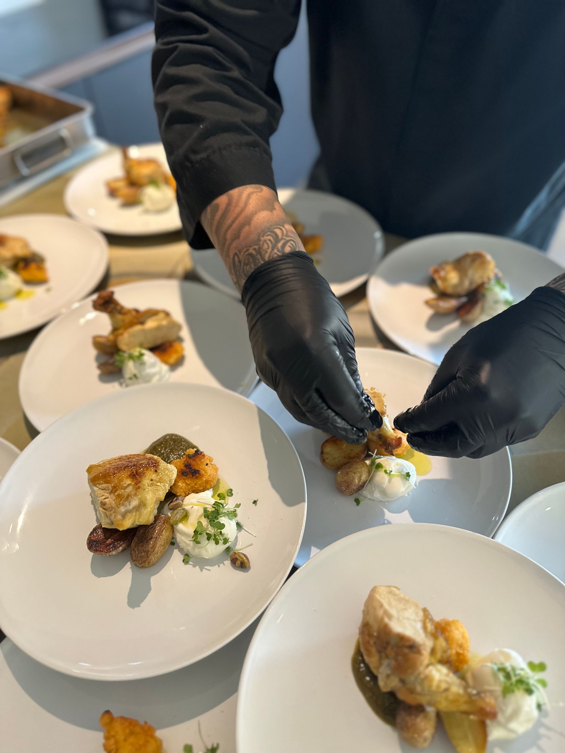Dressage d’un plat par un chef portant des gants noirs