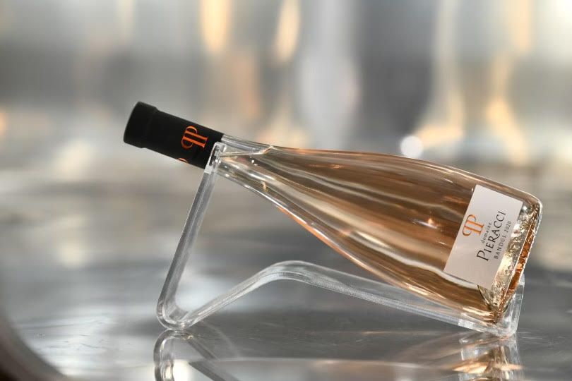 Bouteille de rosé du Domaine Pieracci posée sur un support design, avec reflet métallique en arrière-plan.