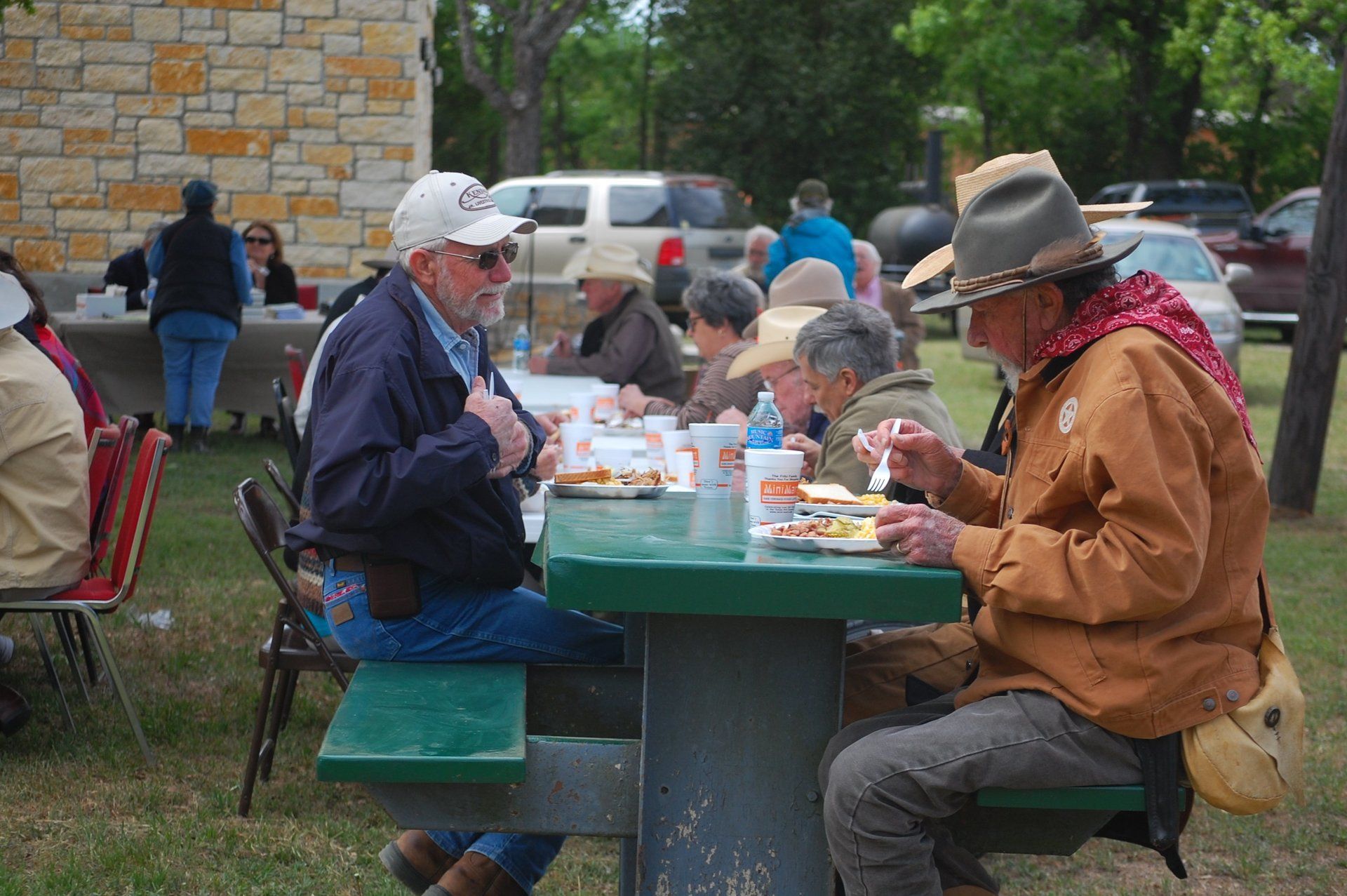 Men eating barbque at table in the park