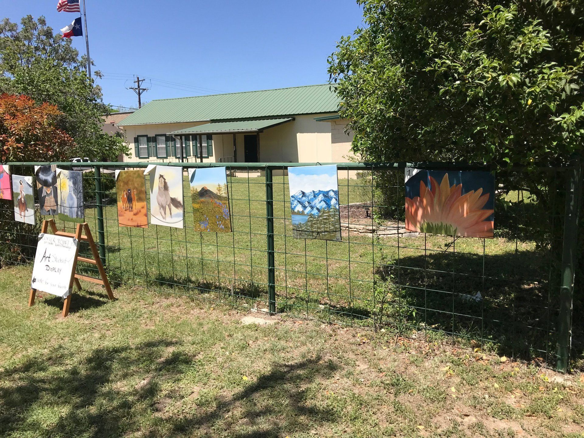 oil paintings hanging on fence