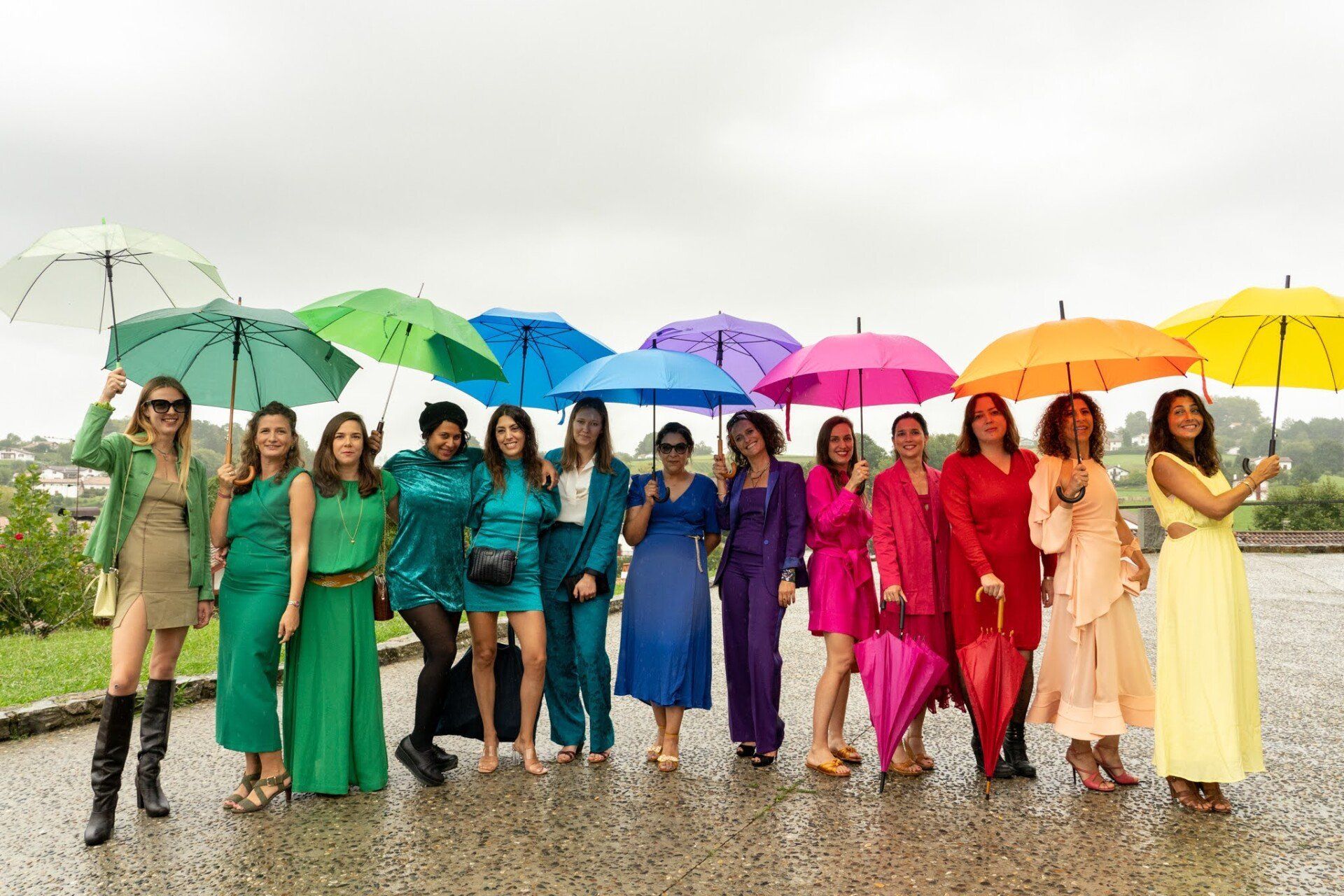 Demoiselles d'honneur arc en ciel Photo sous la pluie représentant 13 demoiselles d'honneur le jour du mariage de leur amie au Pays Basque, à Espelette, chacune étant habillée d'une couleur de l'arc en ciel