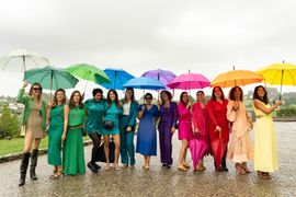 Photo sous la pluie représentant 13 demoiselles d'honneur le jour du mariage, chacune étant habillée d'une couleur de l'arc en ciel