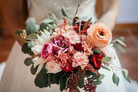 Photo d'un bouquet de mariée, dans les tons de pêche, rouge, rose poudré et violet