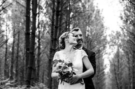 Couple de jeunes mariés enlacés se tenant par la taille le jour de leur mariage dans une forêt des Landes