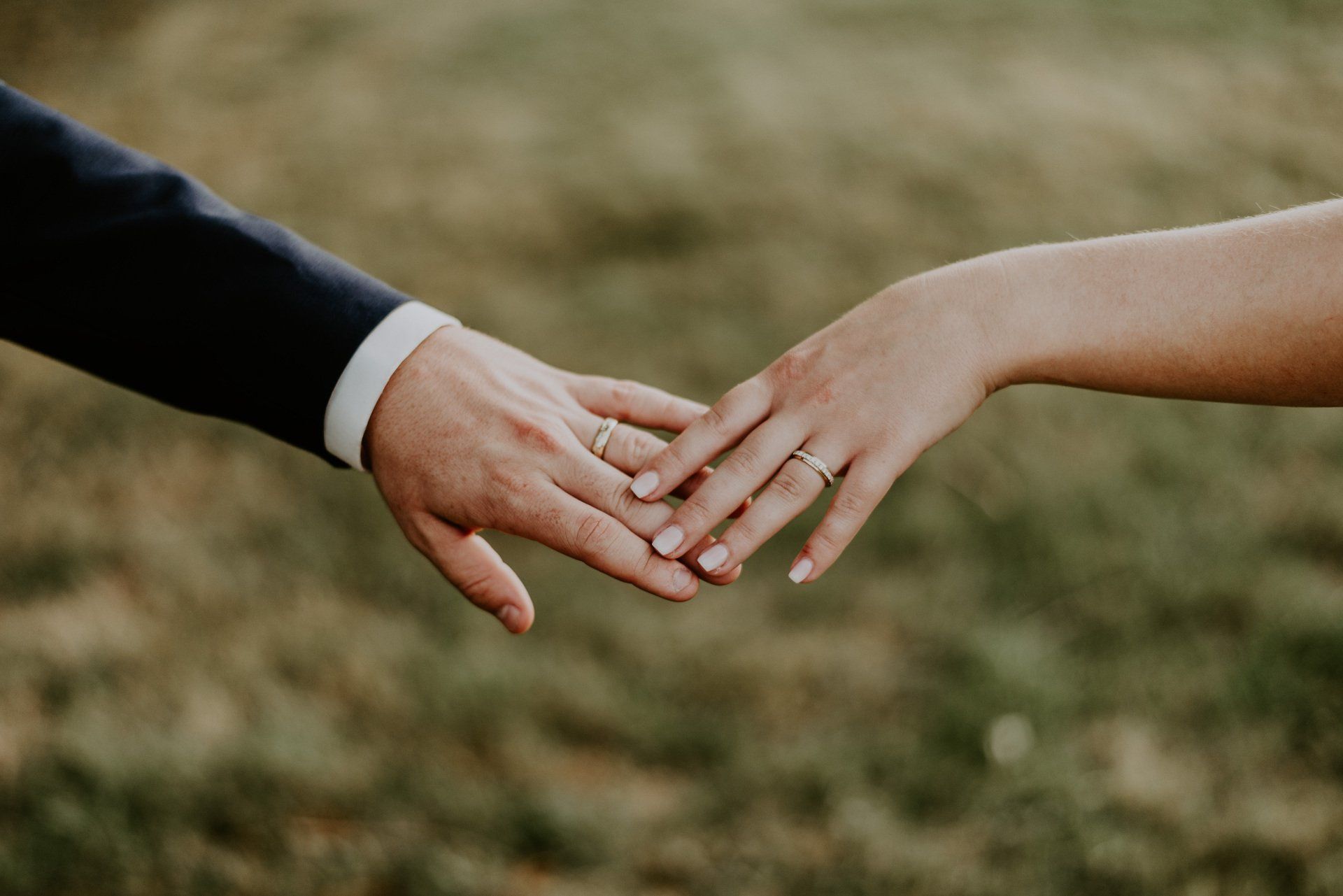 Jeunes mariés Photo de deux mains de jeunes mariés qui se touchent du bout des doigts et nous montrent leurs alliances de mariage