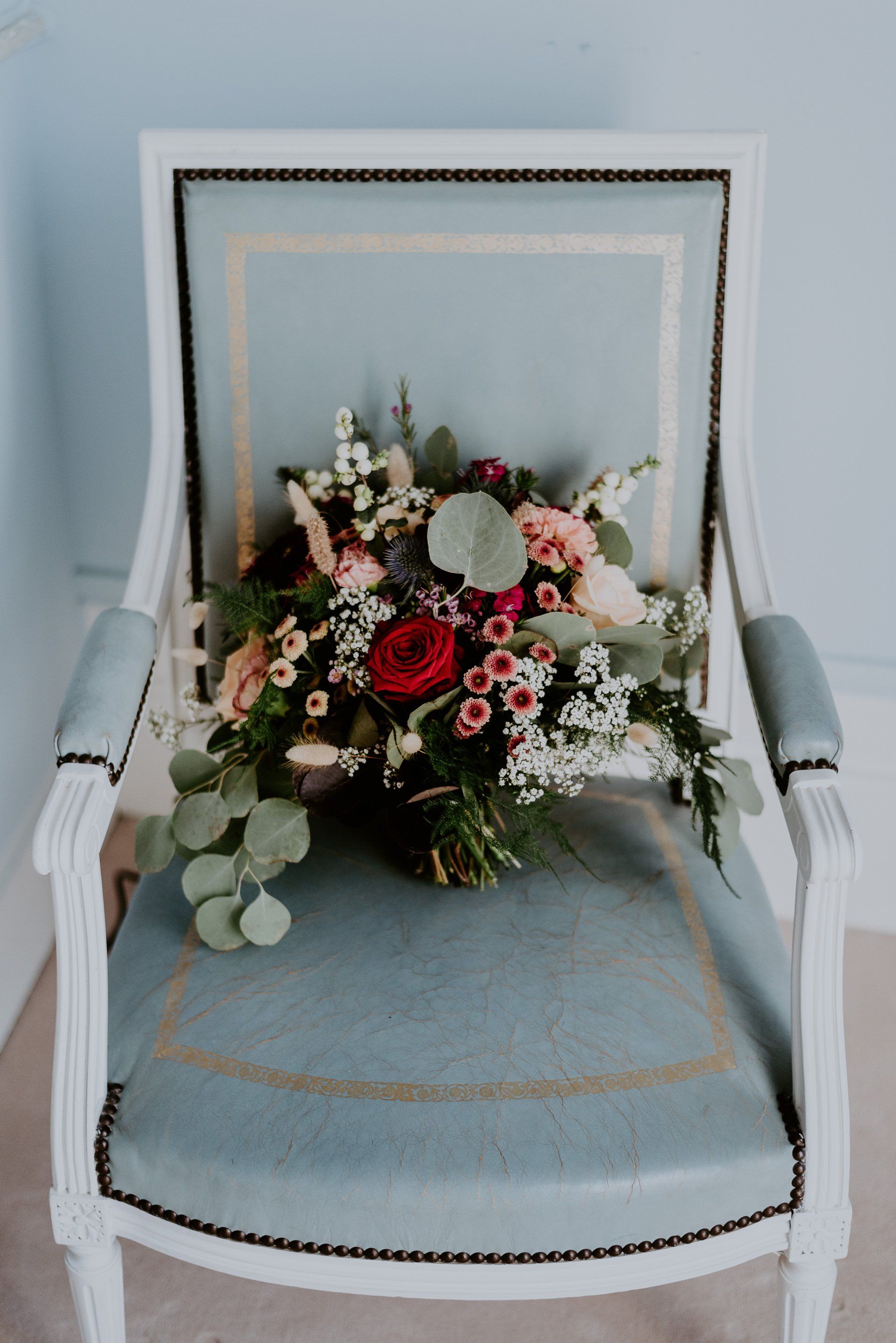 Bouquet de mariée Photo d'un fauteuil ancien, style empire, bleu ciel, avec un bouquet de mariée posée sur l'assise , bouquet aux tons colorés de rouge, bleu, verts, pêche, eucalyptus. Décoration de mariage