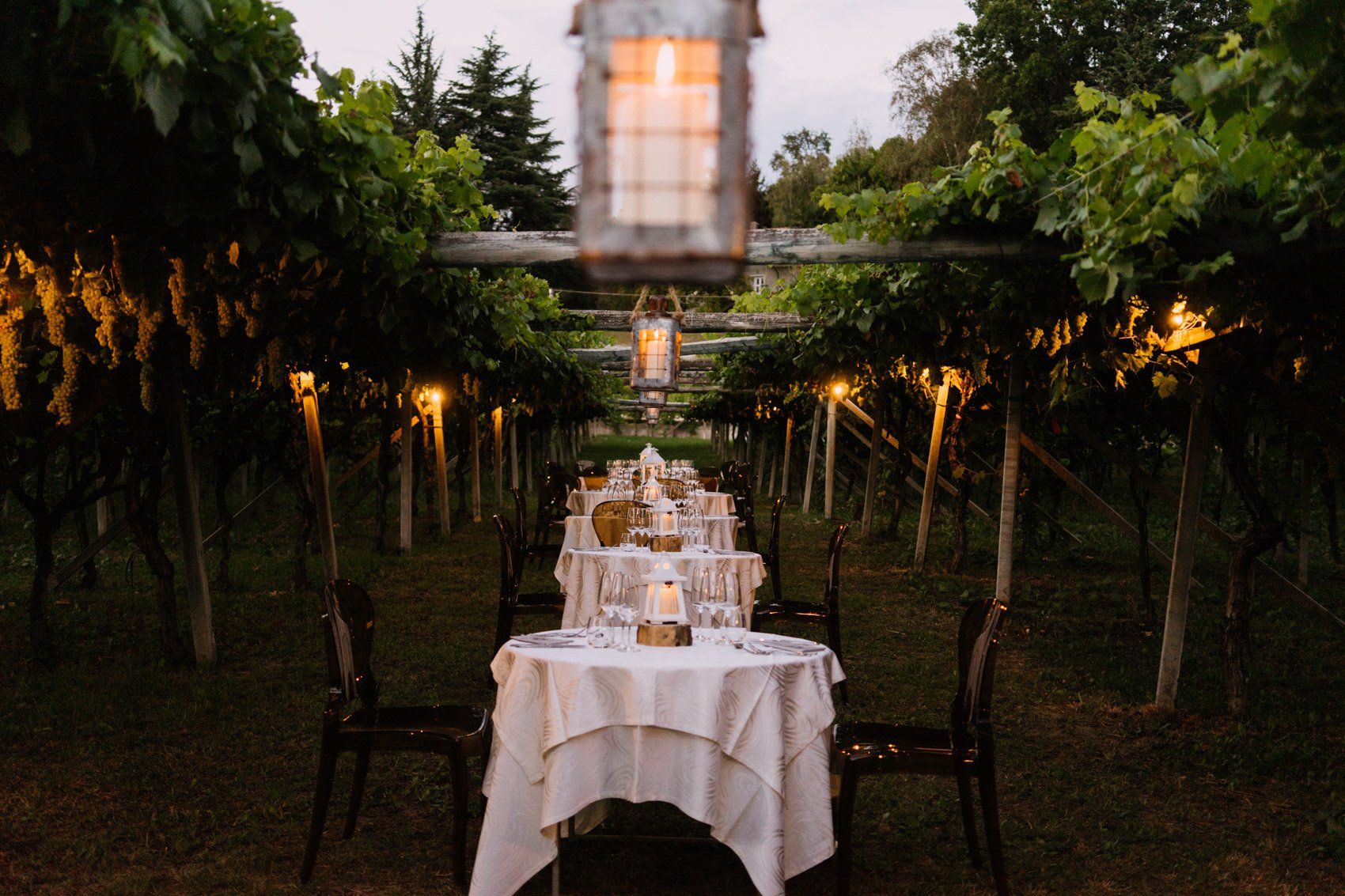 Mariage en extérieur Tables rondes dressées pour un mariage au milieu des vignes, éclairées par des lanternes