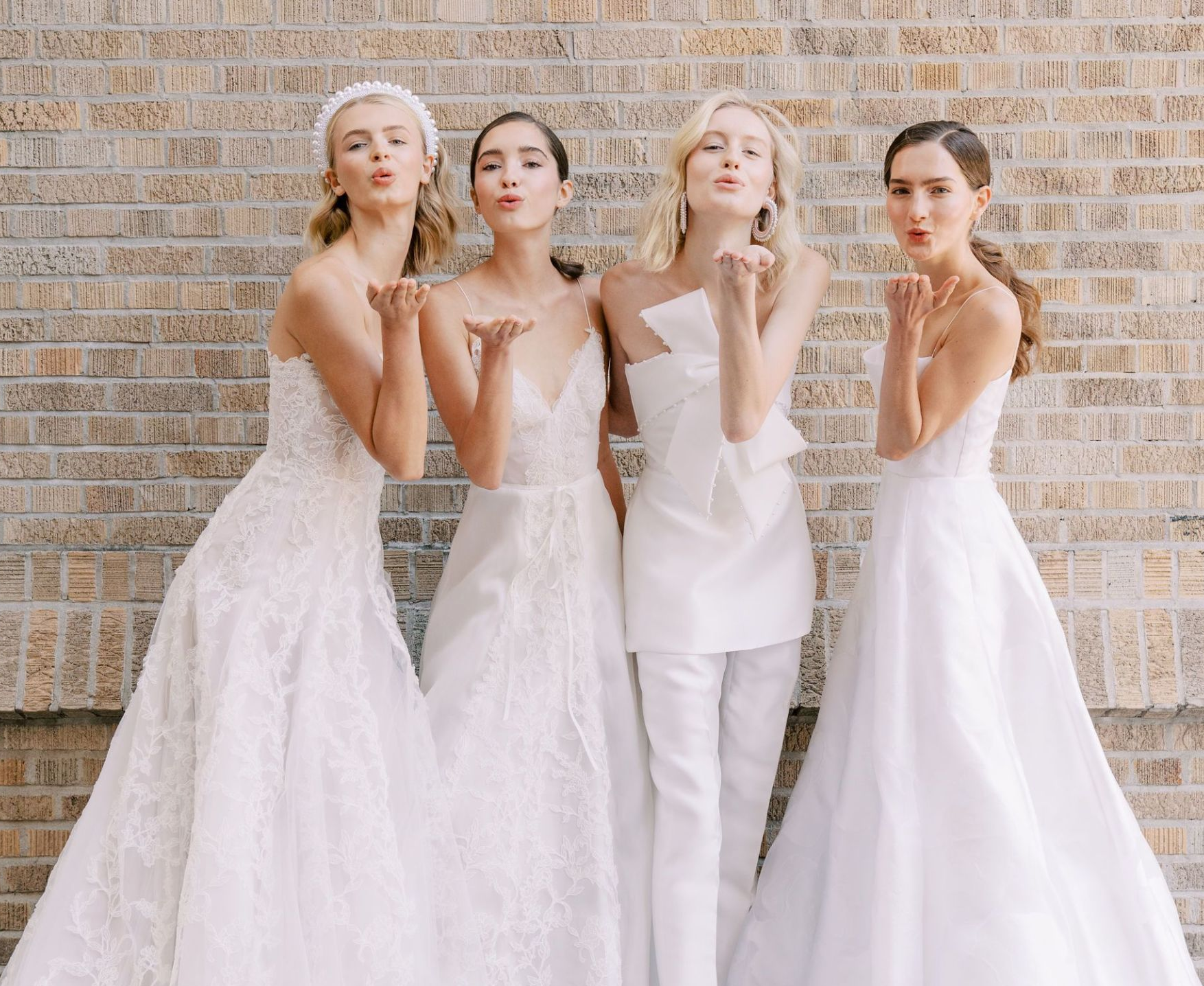 groupe de quatre mariées en robe de mariée faisant le geste d'envoyer un bisou avec leurs mains