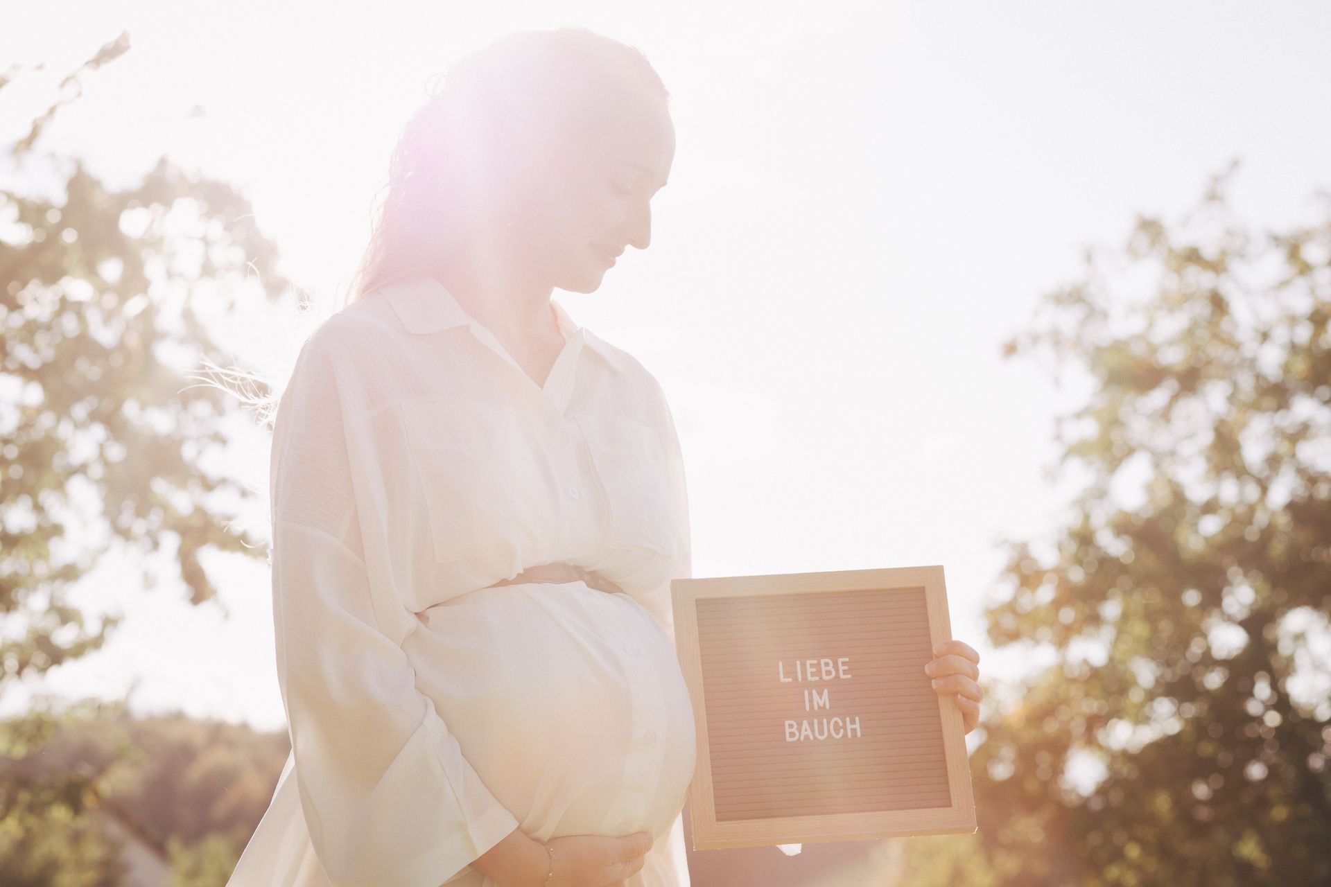 Werdende Mutter zeigt stolz ihren Babybauch in einem einfühlsamen Schwangerschaftsporträt.