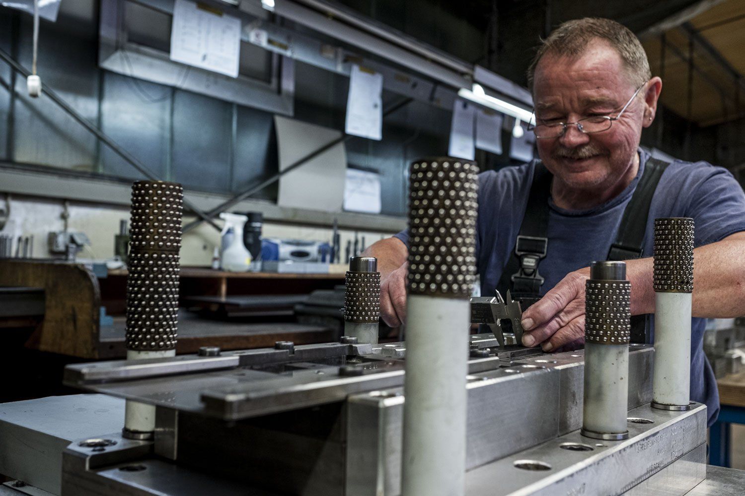 Ein Mann kontrolliert in der Werkstatt mit einem Messschieber Längen.