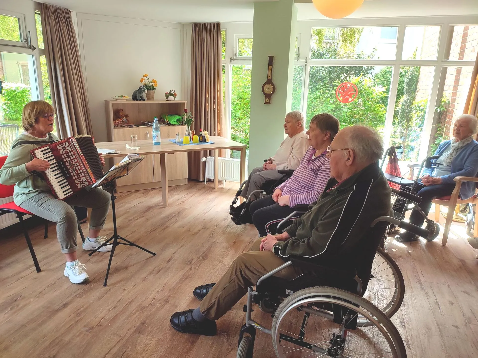 Frau Munzel spielt Akkordeon für Bewohner im Tagesraum.
