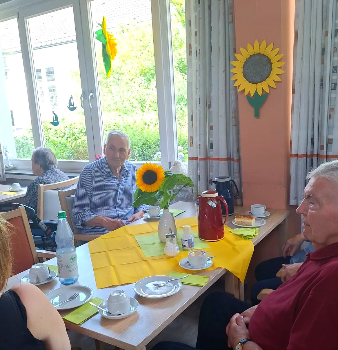 Bewohner sitzen gemeinsam am Tisch bei Kaffee und Kuchen beim Sommerfest.
