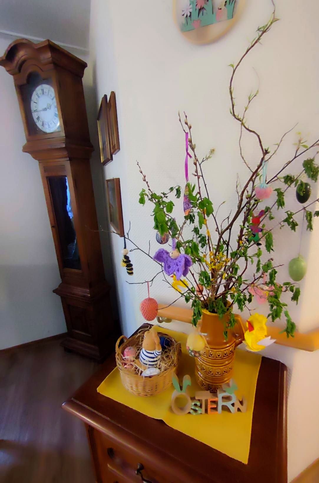 Osterdekoration mit geschmückten Zweigen und Ostereiern auf einer Kommode.