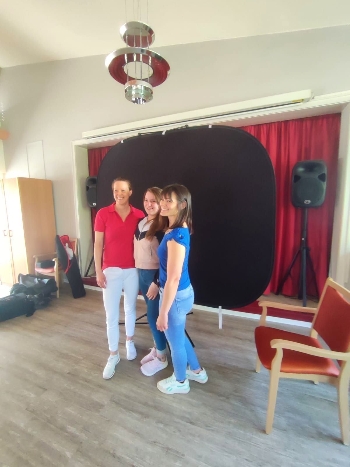 Drei Mitarbeiterinnen stehen beim Fotoshooting vor einer Fotowand im Lambertistift.