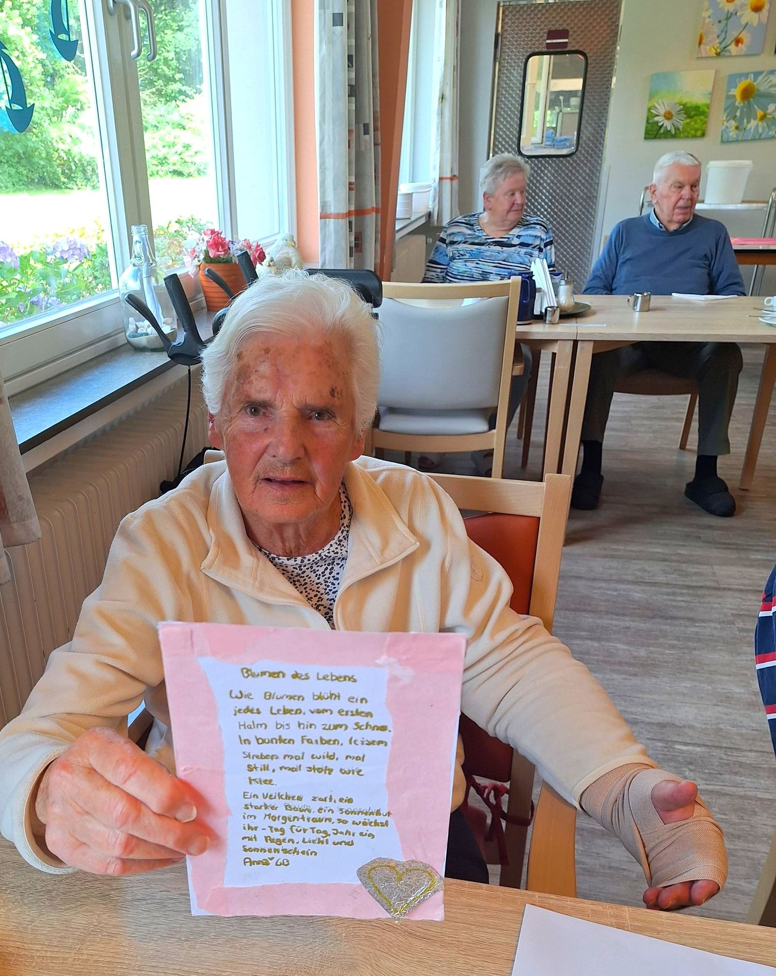 Bewohnerin zeigt eine erhaltene Karte mit einem Gedicht aus der Aktion „Herzenspost“.